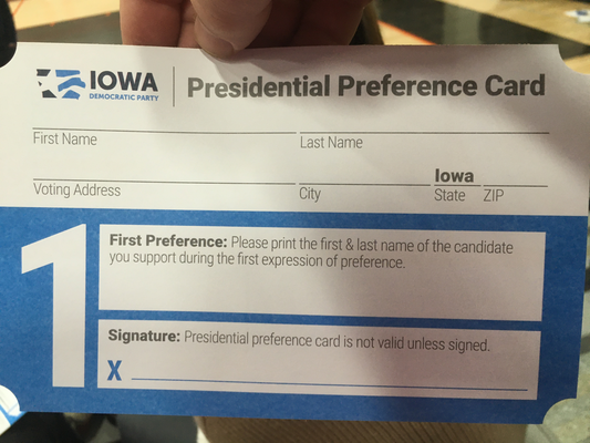A card.  IOWA Democratic Party.  Presidential Preference Card.  An area labeled 'First Name'.  An area labeled 'Last Name'.  An area labeled 'Voting Address'.  An area labeled 'City'.  An area labeled 'State' that is pre-filled with 'Iowa'.  An area labeled 'Zip'.  A big '1'.  An area labeled 'First Preference: Please print the first & last name of the candidate you support during the first expression of preference.'  An area labeled 'Signature: Presidential preference card is not valid unless signed' with a big blue 'X' next to it.