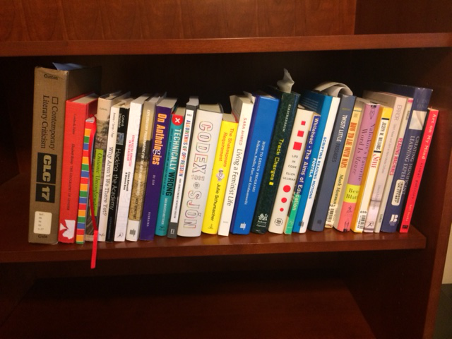 A variety of books on a single shelf of a bookshelf.