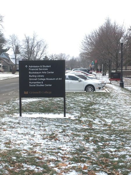 A photo with a sign that has an arrow pointing forward and the terms 'Admission & Student Financial Services', 'Bucksbaum Arts Center', 'Burling Library', 'Grinnell College Museum of Art', and 'Humanities & Social Studies Center'.  In the background are some cars and a sign that reads 'Loose Hall'.