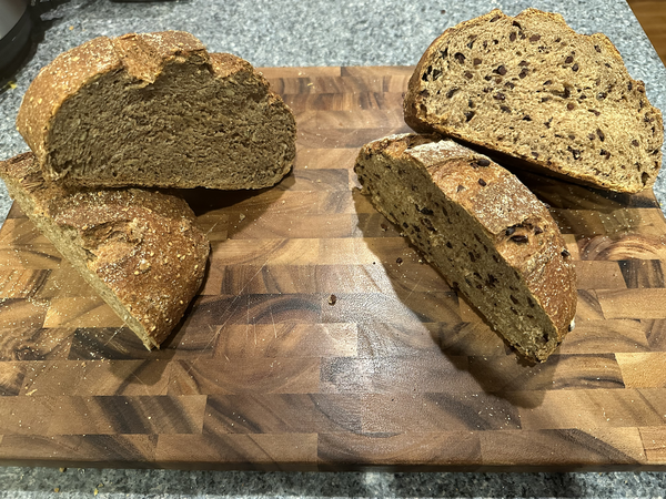 Two round loaves of wheat bread, each cut in half.