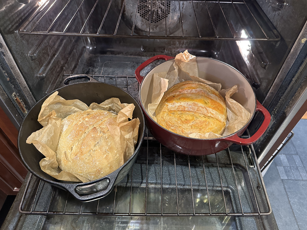Two round loaves of white bread in Dutch ovens; the one on the right looks a bit orange, presumably from the cheese.